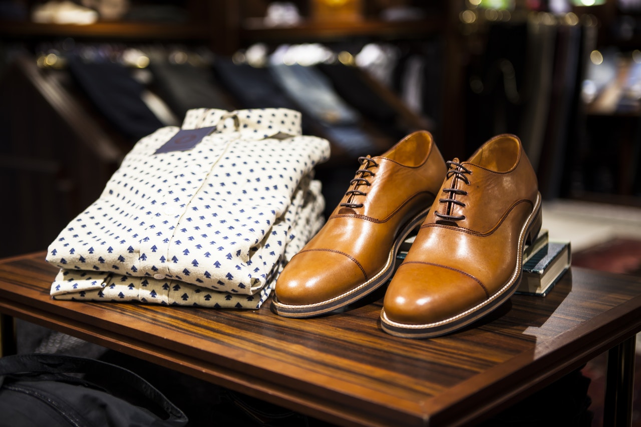 Polka dot white and blue dress shirt next to a pair of mens light brown oxford shoes